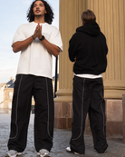 Ahmed og Mathias i vores straight fit Track Pants. Detaljeret med refleksstriber, vores signatur metal branding og et tidløst og stilrent monokromt logo.